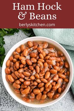 a white bowl filled with ham and beans on top of a blue towel next to parsley