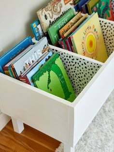 a white wooden box filled with books on top of a floor