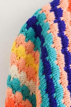 a knitted sweater with multicolored stripes on the top and bottom, close up