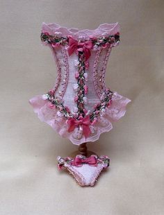 a pink and white corset is sitting on a table next to a teddy bear