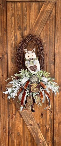 an owl sitting on top of a wreath next to a wooden door with a knife