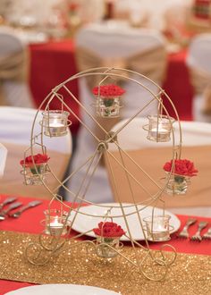 a ferris wheel decorated with red roses on a table at a wedding or reception venue