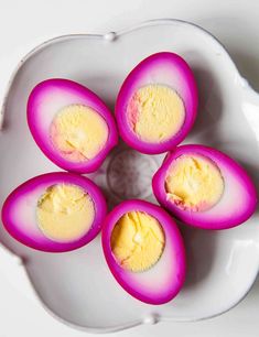 four pieces of deviled eggs on a white plate with yellow paste in the center