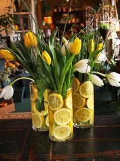 three vases filled with lemon slices and flowers