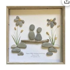 three pebbles sitting on a branch with flowers and grass in the middle, surrounded by rocks