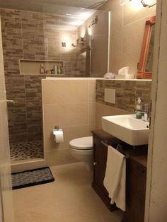 a bathroom with a sink, toilet and shower stall in the background is tiled walls