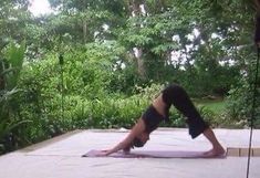 a woman is doing yoga in the middle of an outdoor area with trees and bushes