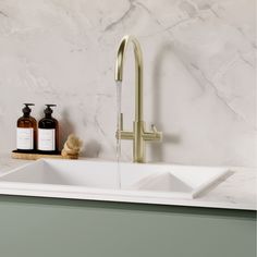 a kitchen sink with soap and lotion next to it on a marble countertop