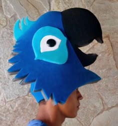 a person wearing a blue bird hat with black eyes