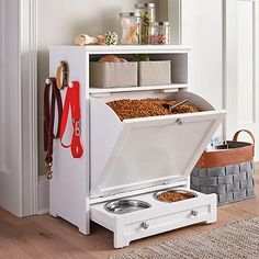 a white cabinet with drawers and two bowls in it next to a rug on the floor