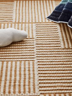 two pillows and a stuffed animal on a carpeted area with vertical lines in the background