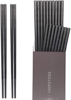 six black chopsticks in a box with the top open and one on it's side