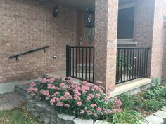 a brick house with flowers in the front yard and stairs leading up to the door