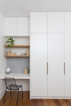 a white closet with shelves and a chair next to it on a hard wood floor