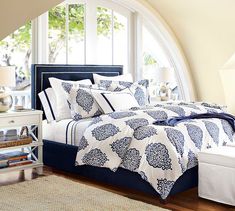 a bed with blue and white bedspread in a bedroom next to a window