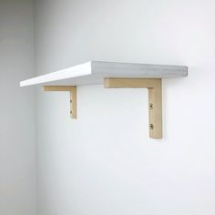 a white wall with two wooden shelves on the opposite side and one shelf above it