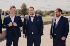 three men in suits and bow ties standing next to each other smiling at the camera