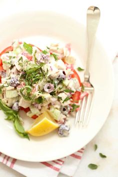 a white plate topped with salad next to a fork