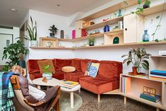 a living room filled with lots of furniture and plants on top of bookshelves