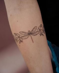 a woman's arm with a dragonfly tattoo on it