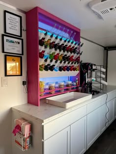 a white counter topped with lots of different colored shoes next to a wall filled with framed pictures