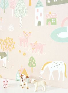 two toy animals are standing in front of a pink wall with farm scenes on it