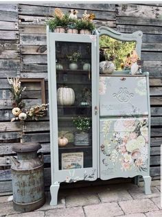 an old china cabinet with flowers and pumpkins on it