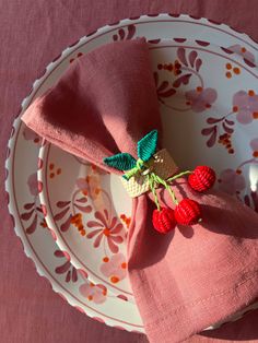 a pink napkin with two strawberries on it sitting on a plate next to a fork and knife