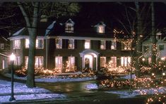 a large house with christmas lights on it's windows and trees in the front yard