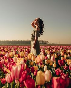 a woman standing in a field of tulips with her hands on her head