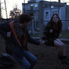 a man and woman holding hands on a swing