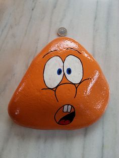 an orange rock with a face painted on it