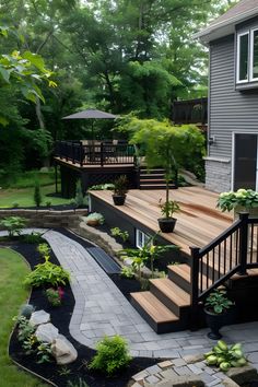 a deck with steps leading up to it and plants on the other side, in front of a house