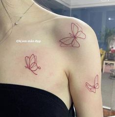 two butterflies on the back of a woman's shoulder, both with red ink