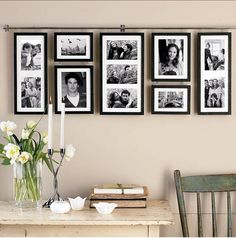 a bunch of pictures hanging on the wall above a table with a vase and flowers