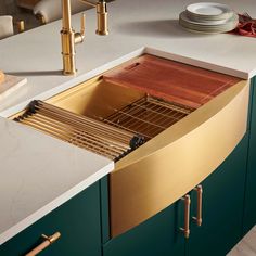 a kitchen with green cabinets and a gold sink in the center is surrounded by white countertops