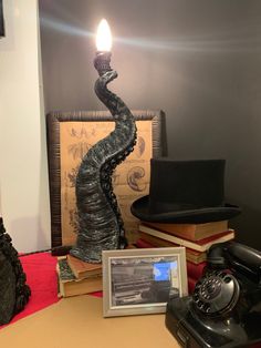 an old fashioned telephone sitting on top of a table next to books and a candle