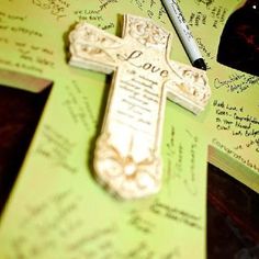 a cross with writing on it sitting next to a pen and some papers that have been written on them