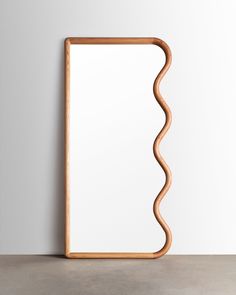 a wooden frame with wavy lines on the front and sides, against a white wall