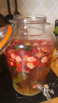 a glass jar filled with sliced strawberries on top of a stove