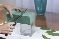 a person cutting into a piece of green cake with a pair of scissors on it