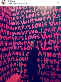 a woman standing in front of a pink wall with letters on it and the word love spelled