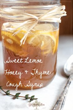 a mason jar filled with honey and thyme cough syrup next to a silver spoon