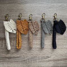 four key chains with different colored tassels hanging from them on a wooden surface