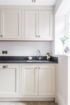 a kitchen with white cabinets and black counter tops in the center, along with an open window