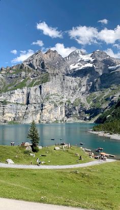 people are sitting at the edge of a mountain lake