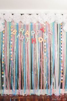 a backdrop with streamers and confetti for a birthday party that is decorated in pastel colors