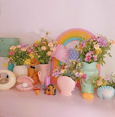 there are many vases with flowers and seashells on the shelf next to each other