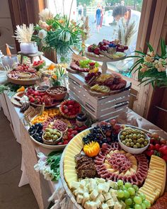 an assortment of cheeses, fruits and meats on display at a buffet table