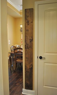 a tall wooden ruler sitting in the middle of a room next to a table and chairs